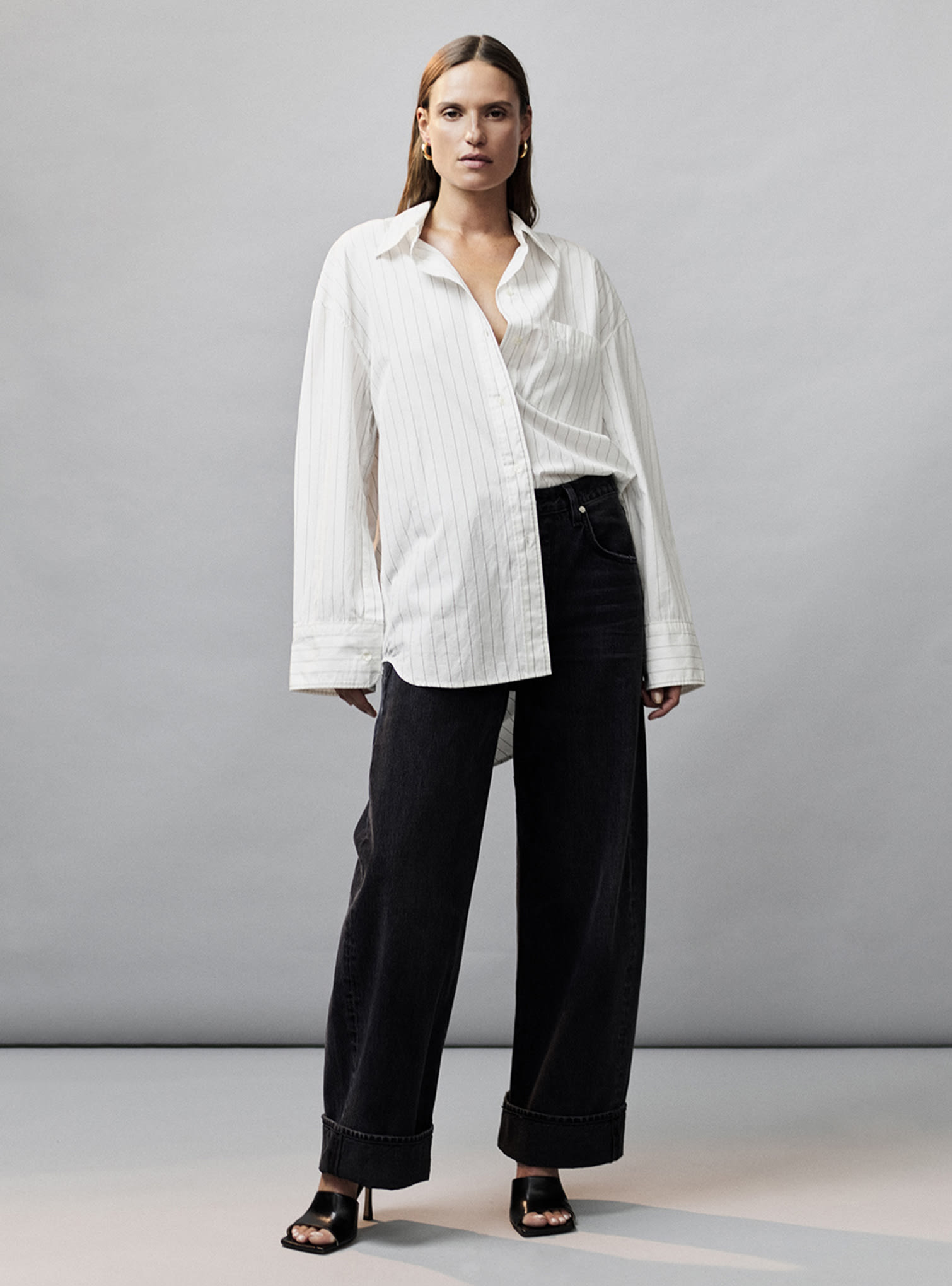 Vaqueros negros de puños anchos, mules negros y camisa blanca a rayas