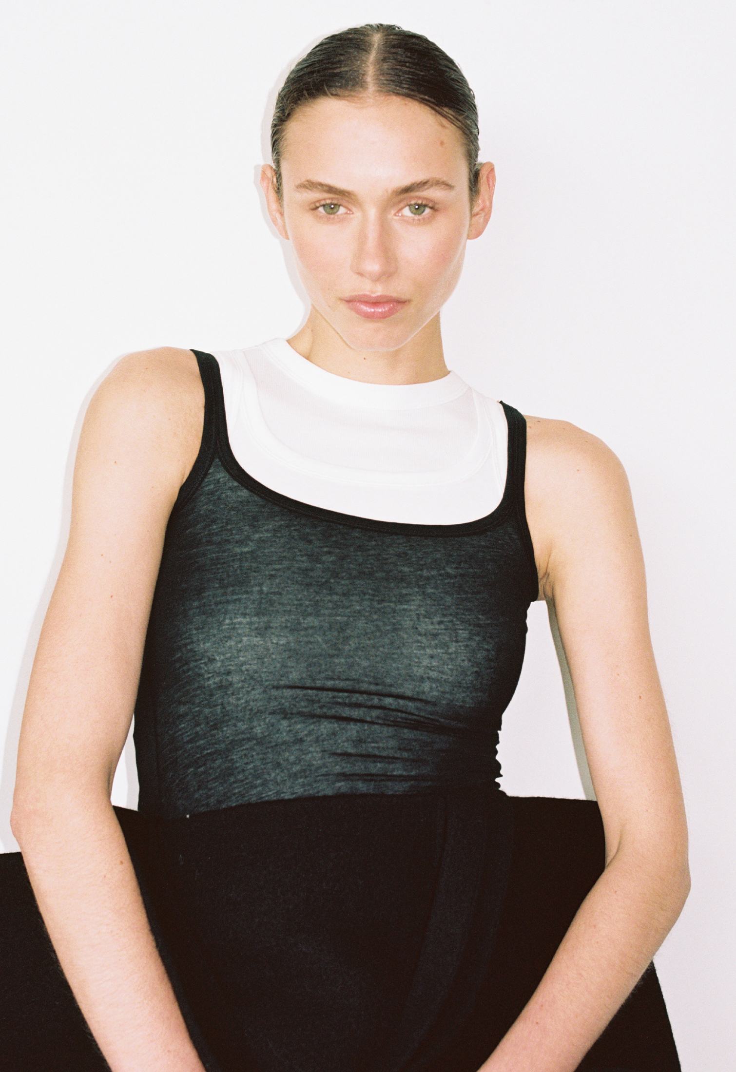 Woman wearing layered tank tops and hold a large bag
