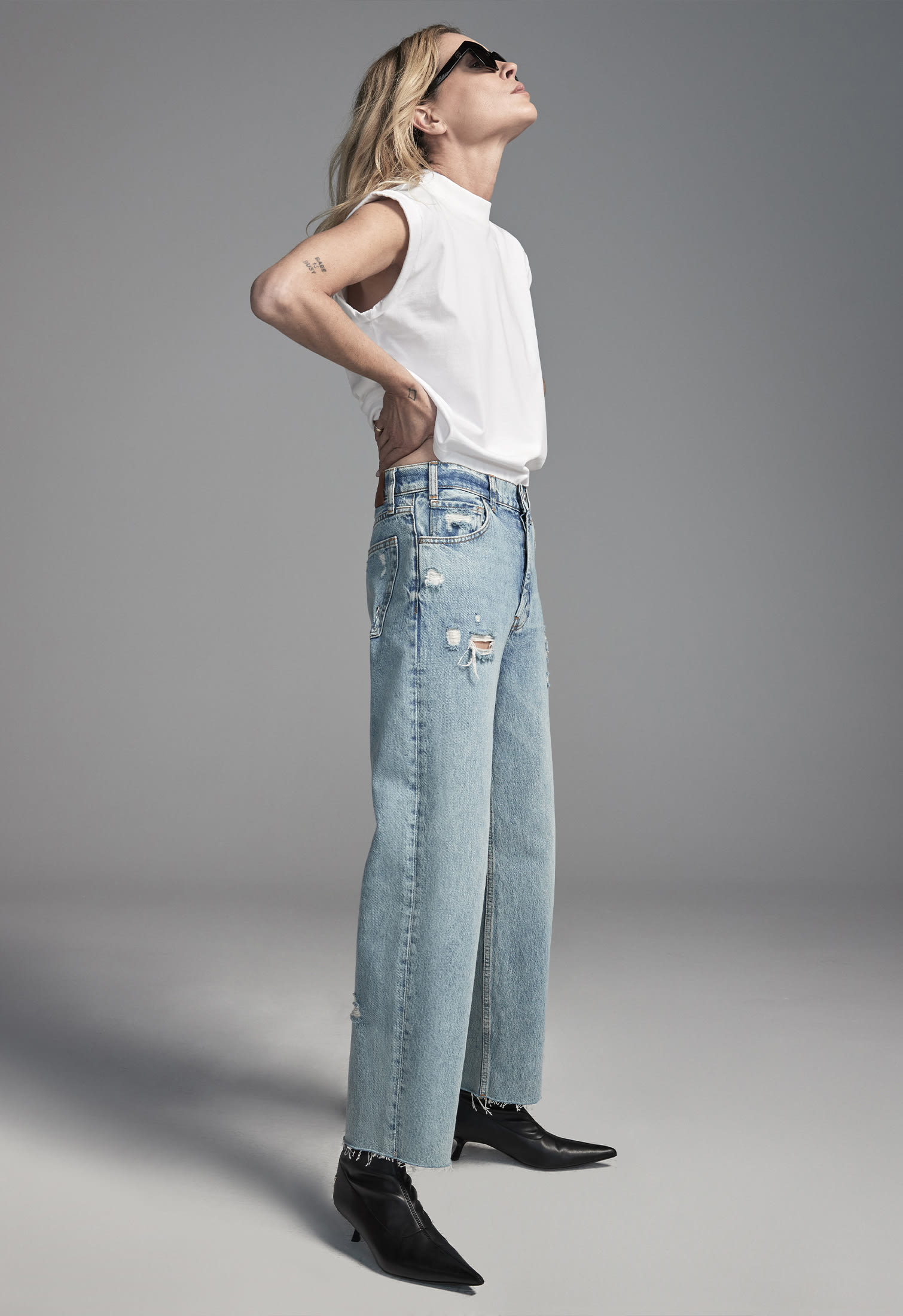 woman in a contemporary outfit of ripped jeans, sleeveless tee and black boots