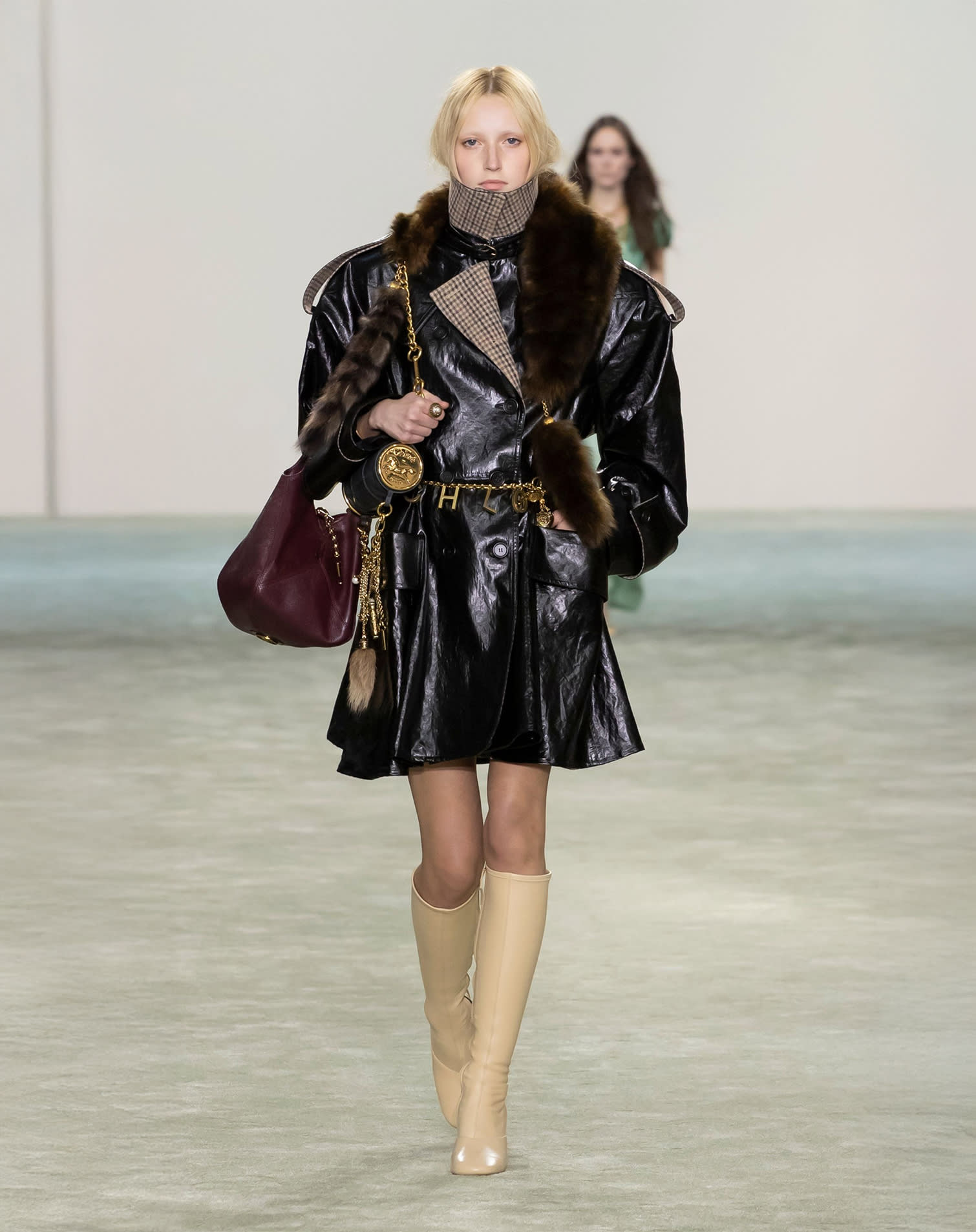 Model wearing leather jacket, beige knee-high boots and burgundy bag