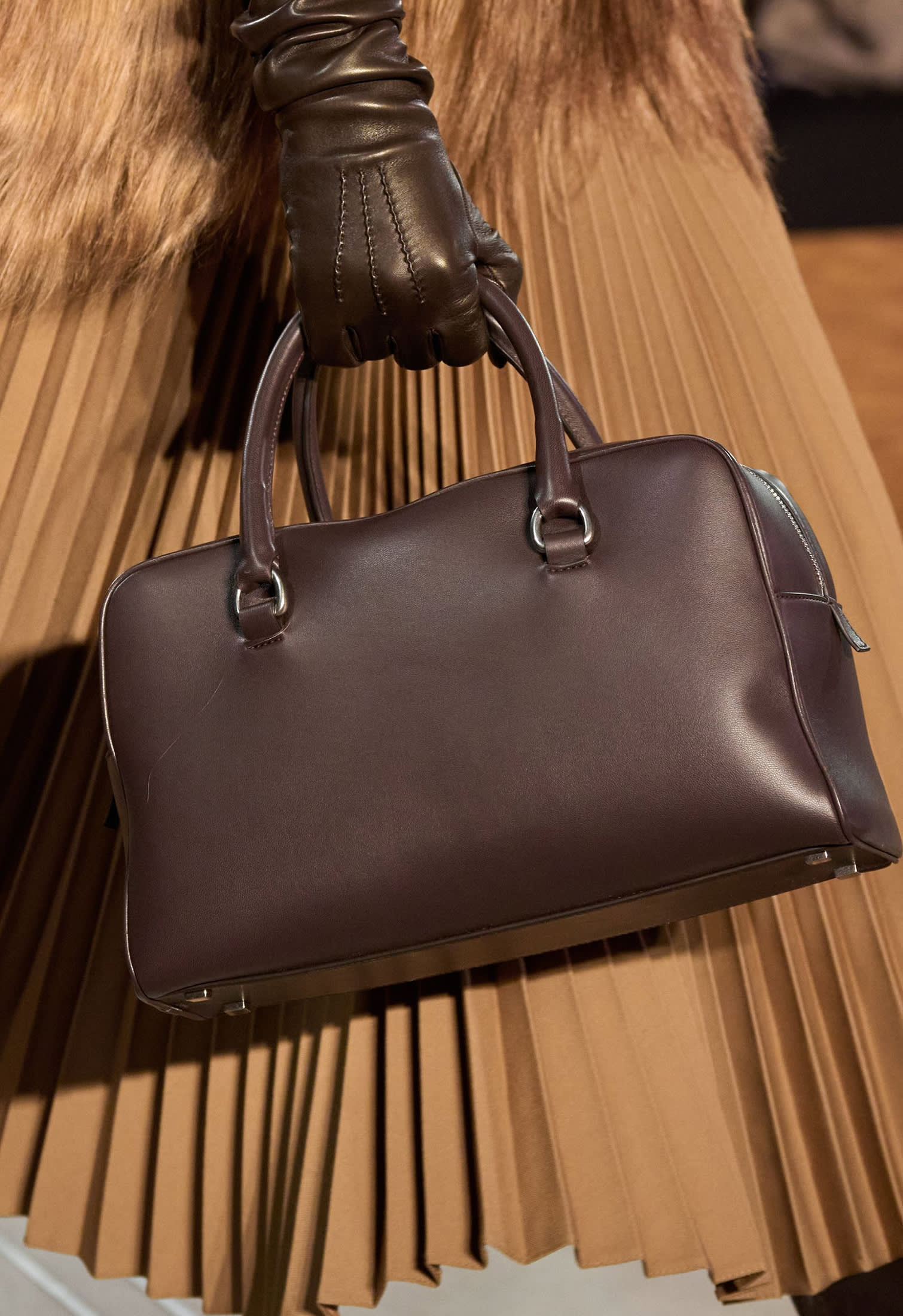 Model with camel plissè skirt and dark brown dostor bag