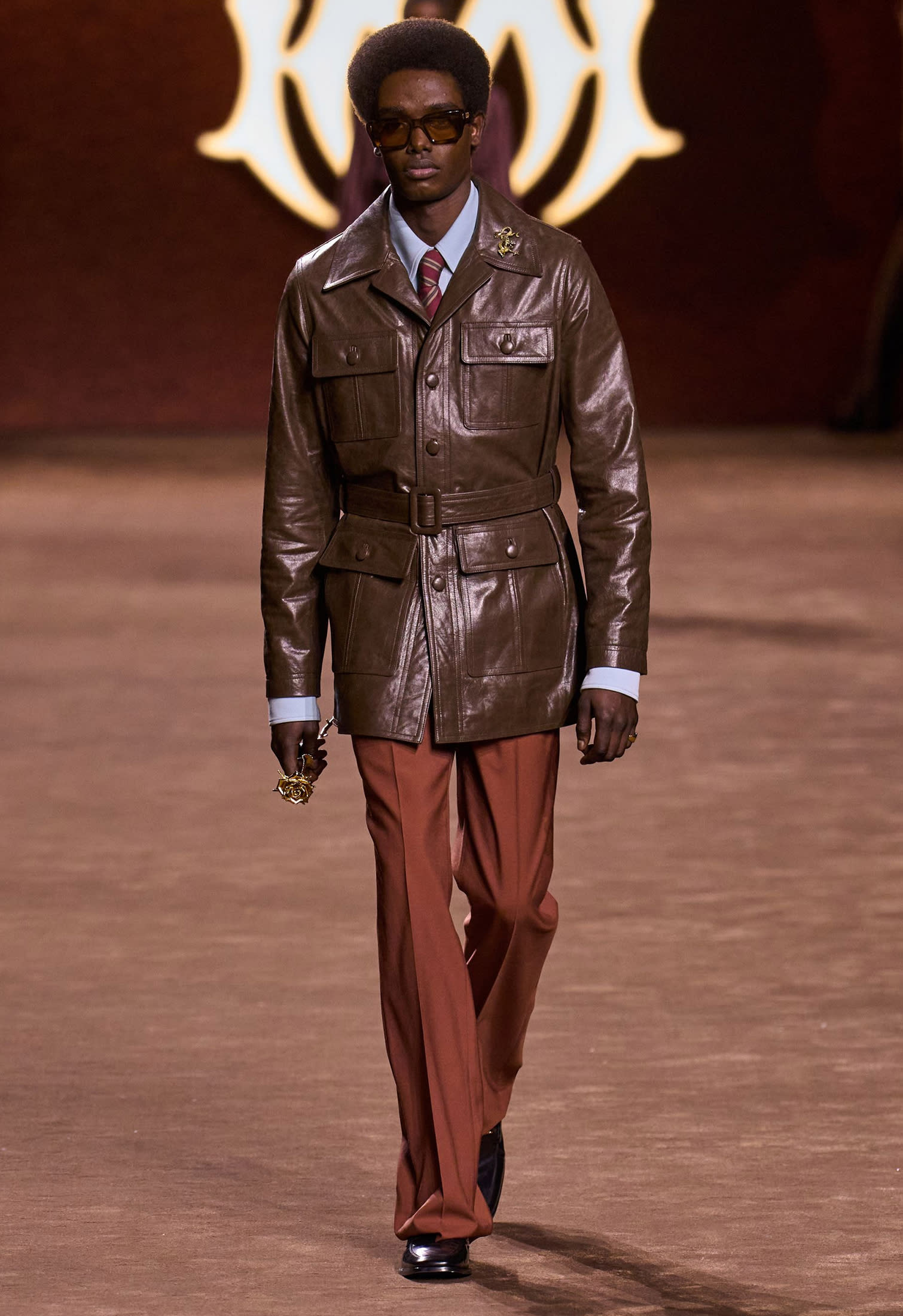 Model wearing a brown leather trench coat with tailored trousers, elegant runway outfit Fall Winter 2025-2026