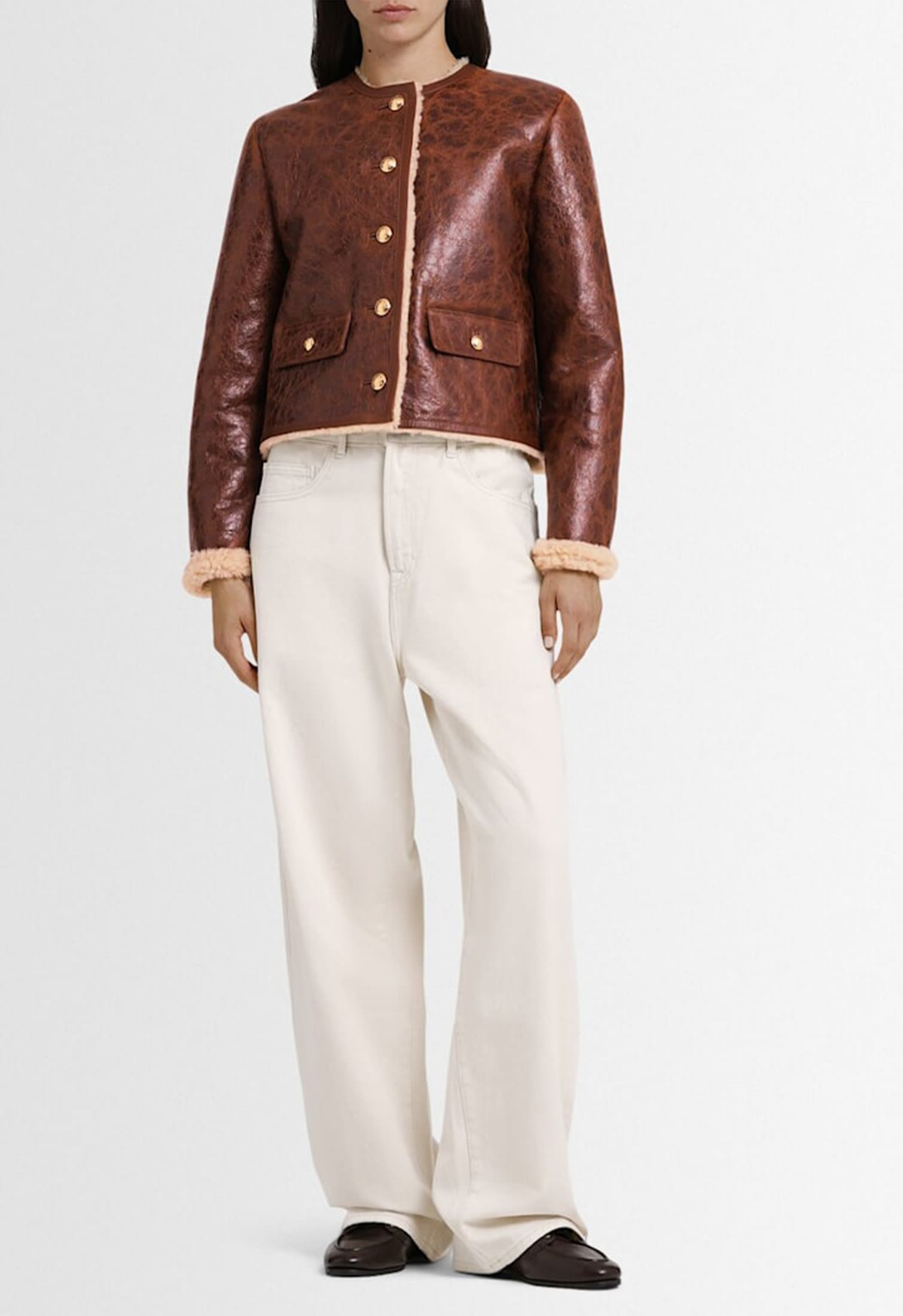 Female model wearing a dark brown shearling leather jacket with cream trousers, classic winter look Fall Winter 2025-2026