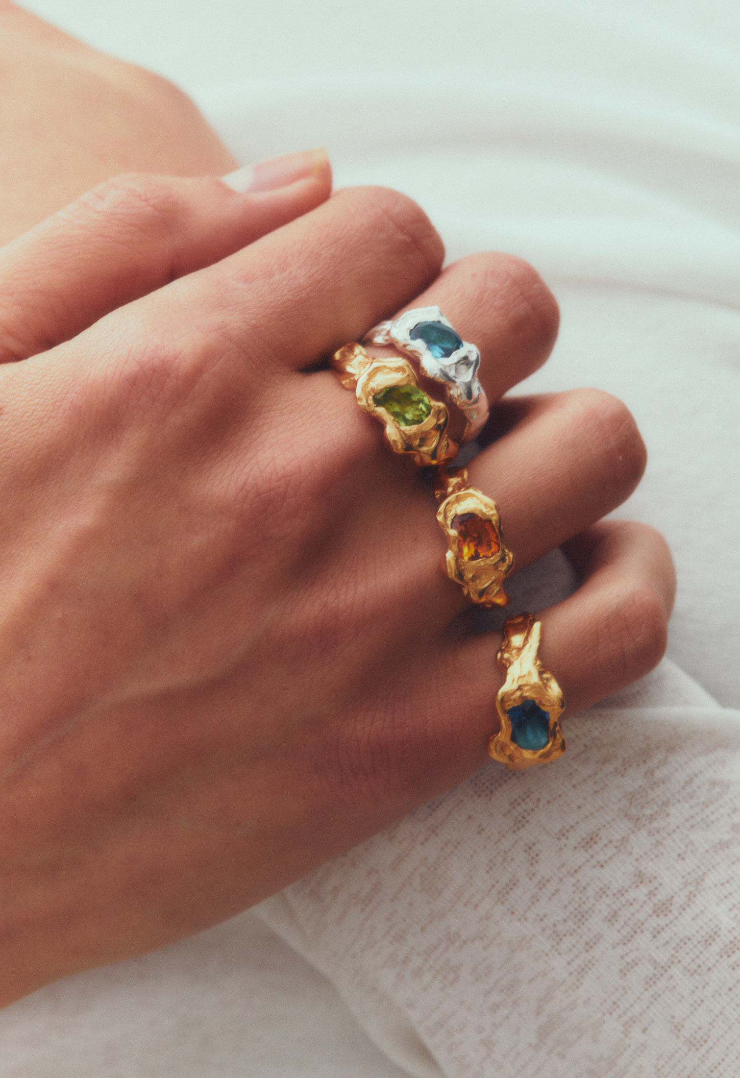 Hand wearing Simuero rings in gold with colorful gemstones, artisanal and contemporary design