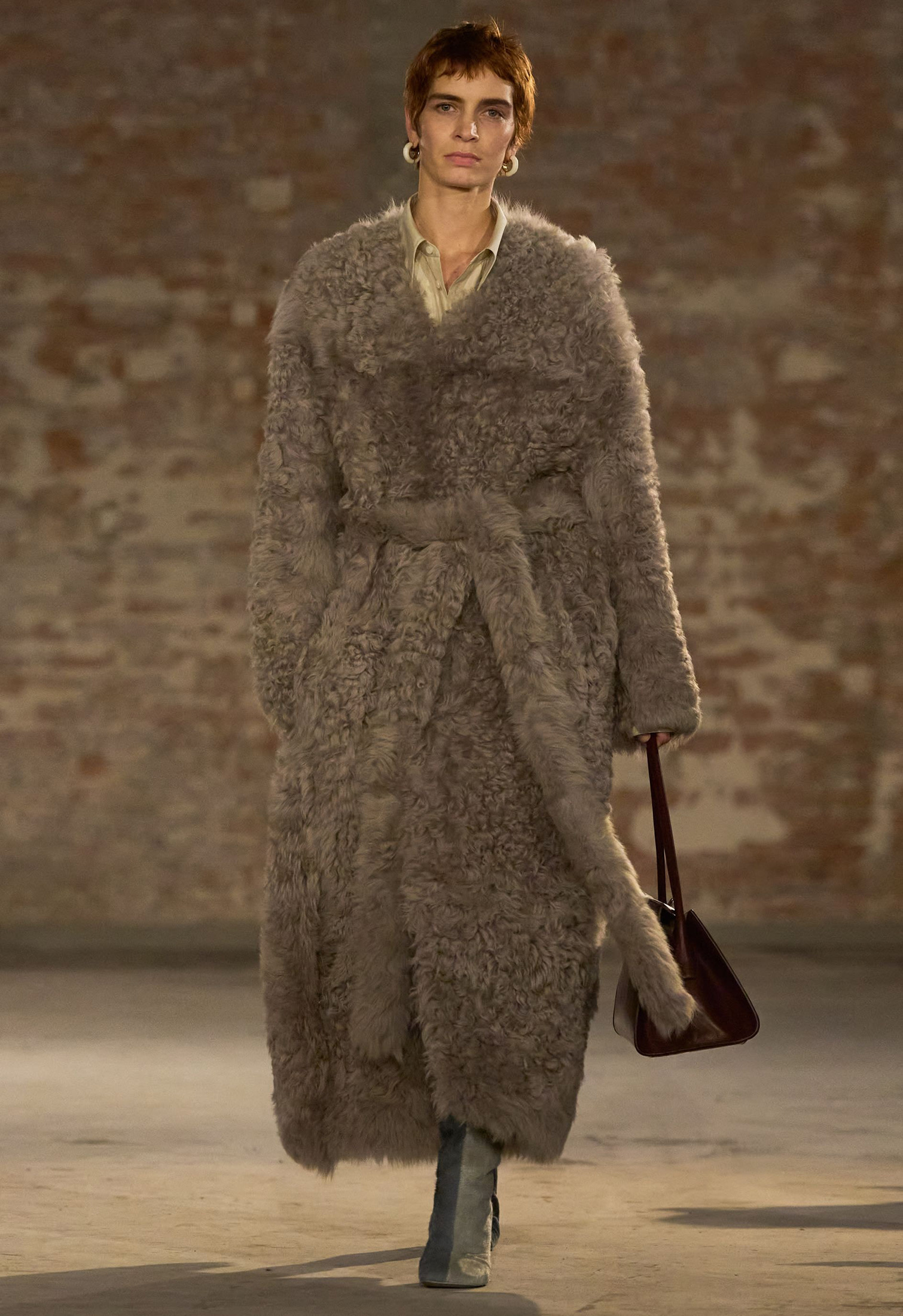 Model in runway with taupe long sheepskin shearling coat by Ami Paris