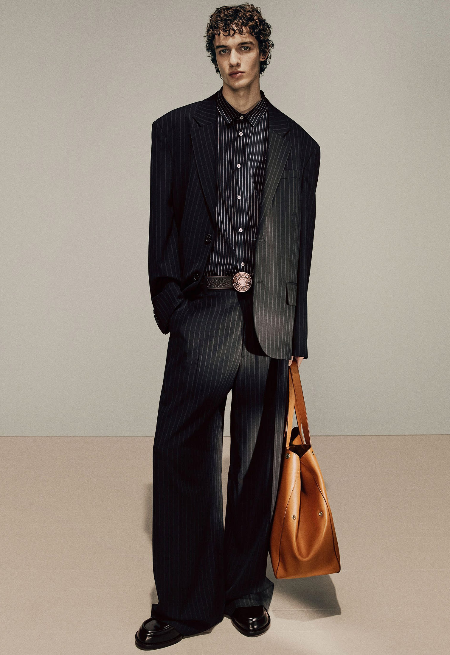 Model with black formal printstripe suit oversize fit and brown leather bag