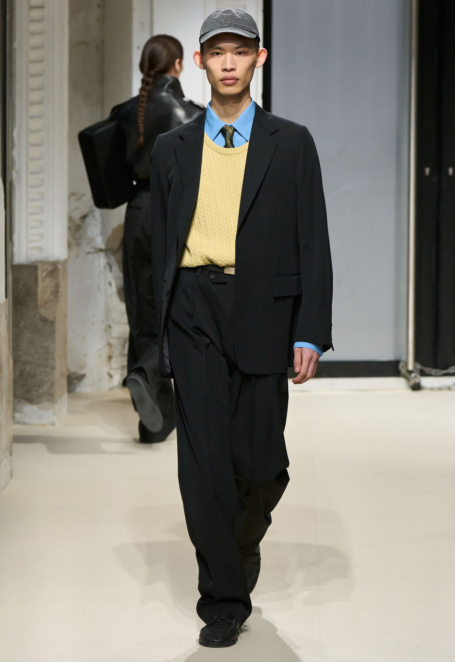 Male model with formal black suit styled with yellow butter sweater and blue shirt