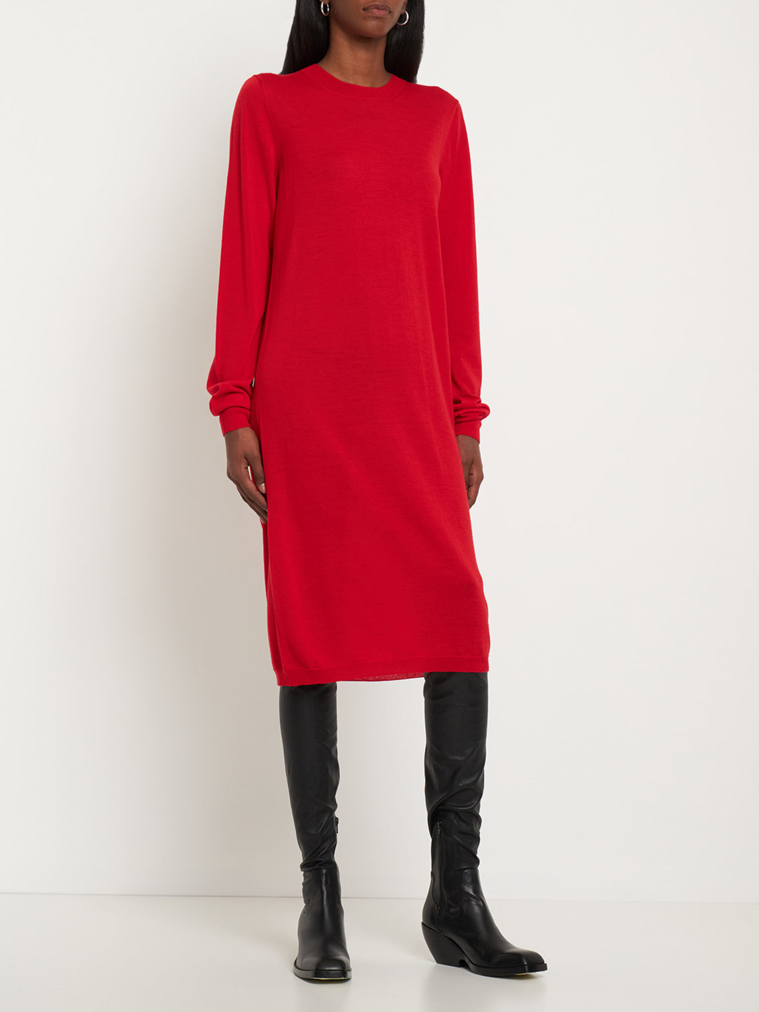 Woman wearing a red long-sleeve knit midi dress styled with black knee-high boots, a minimalist Christmas outfit idea.