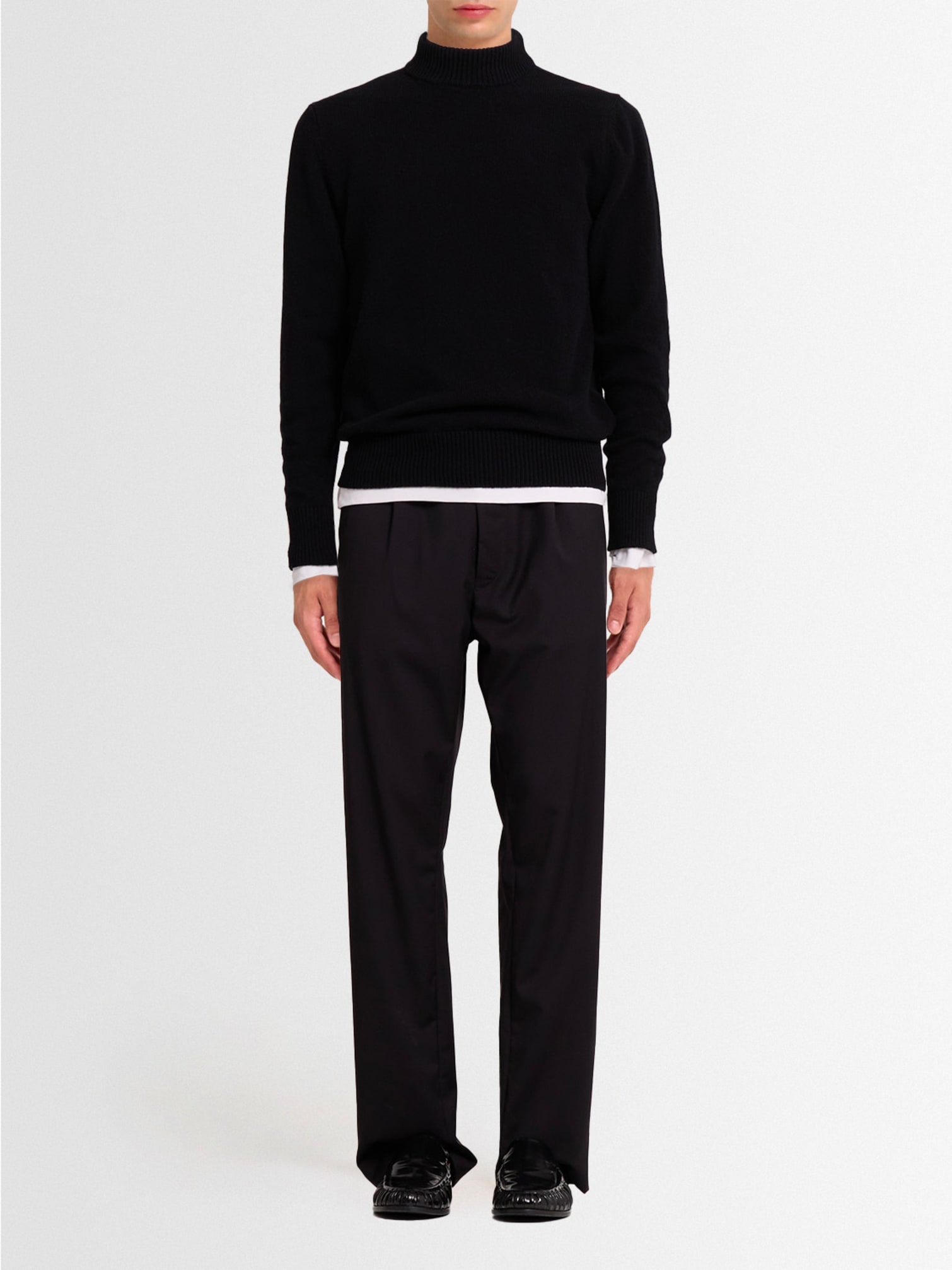 Man wearing a black turtleneck sweater with black tailored trousers and polished loafers, a clean and understated Christmas look.