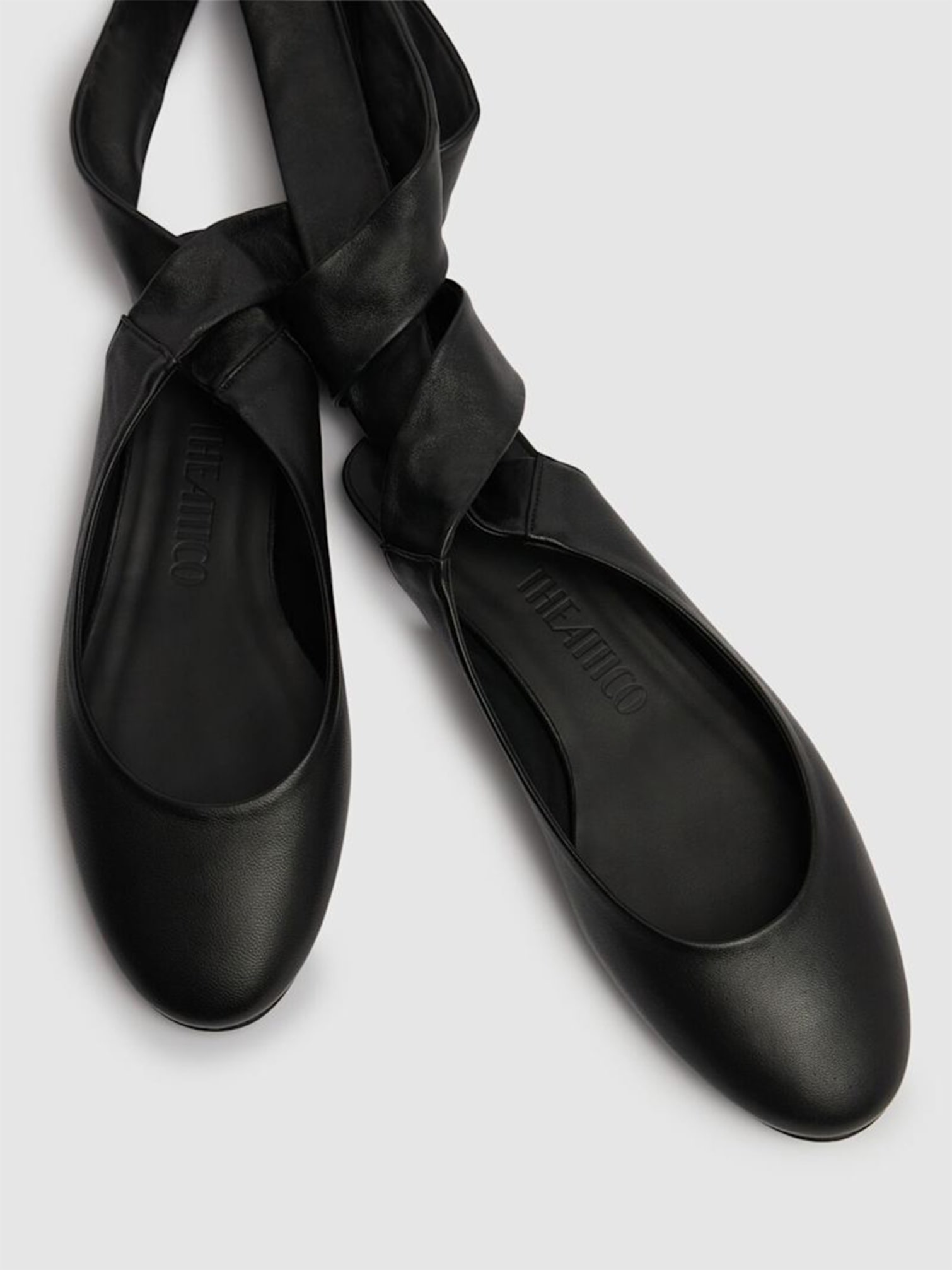 Black leather ballet flats with a soft rounded toe and long ribbons to wrap around the ankle.