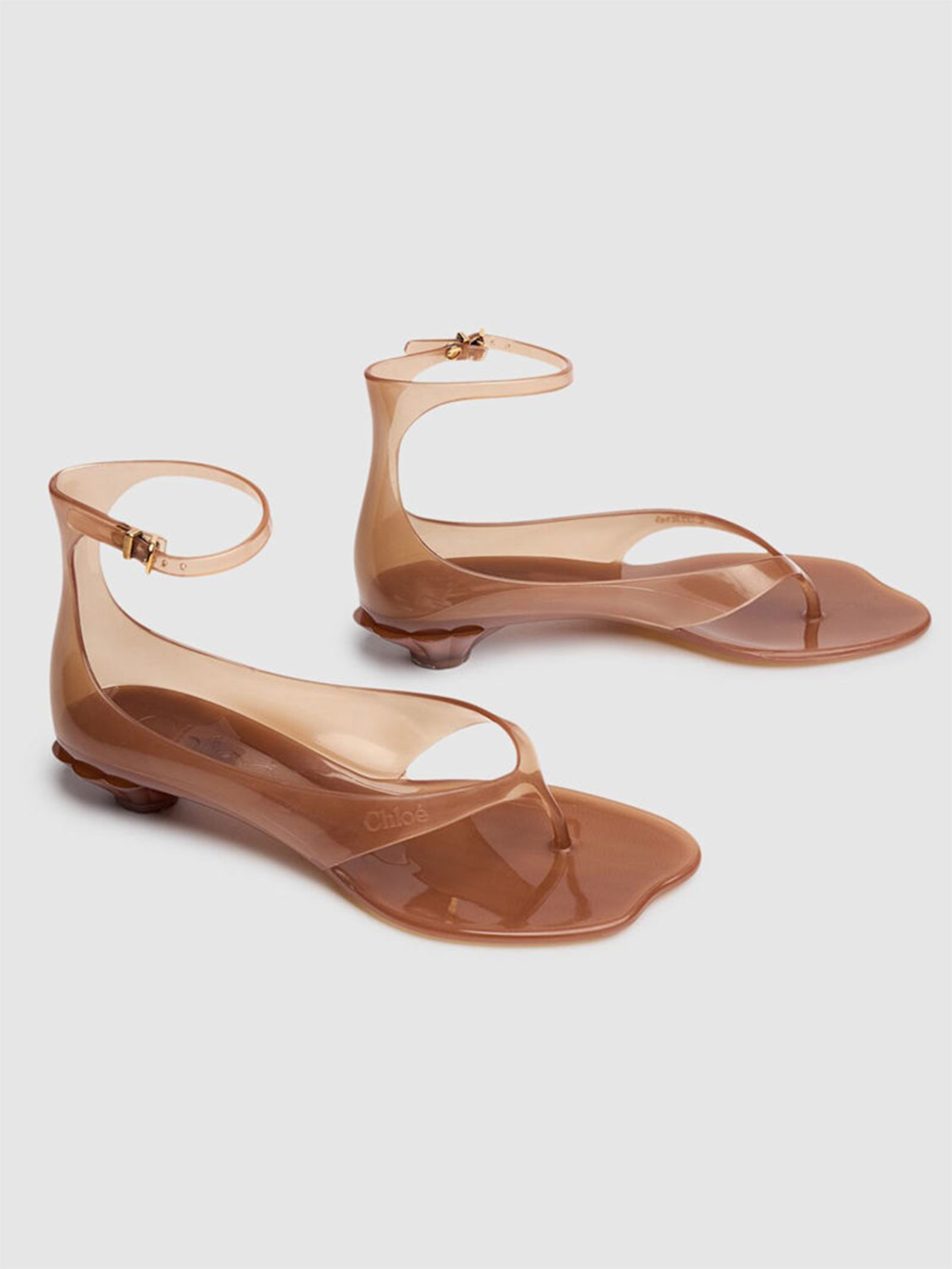 Translucent brown jelly thong sandals with ankle strap.