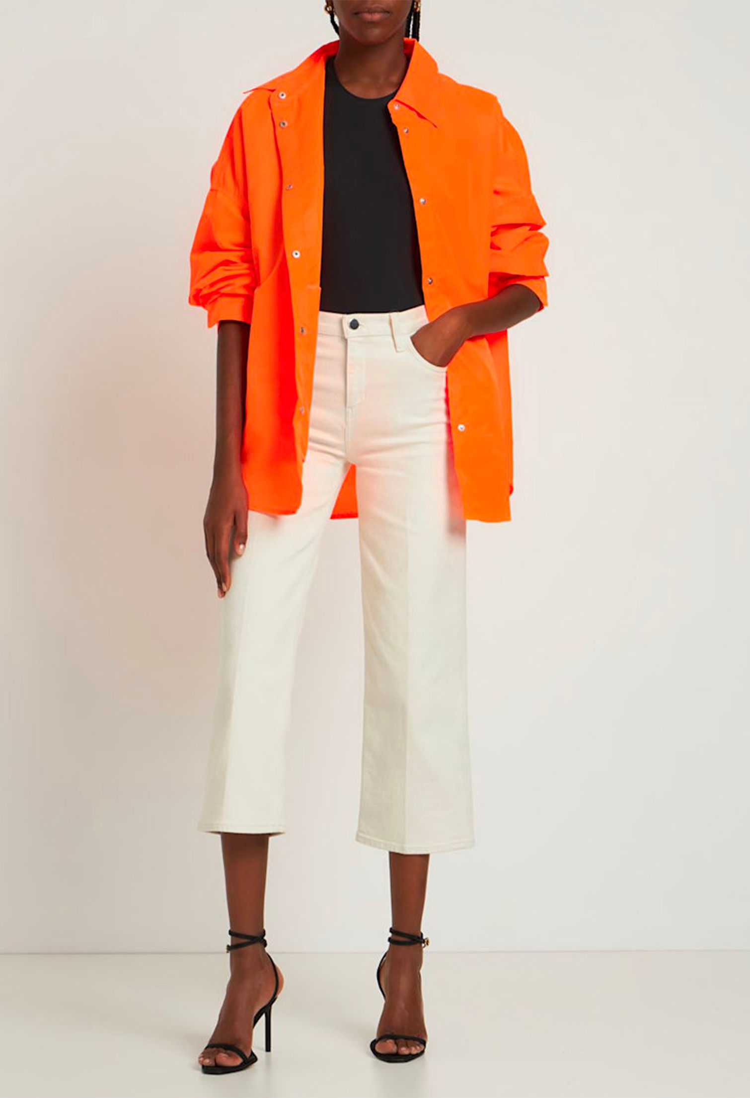 Model with Perla oversize orange shirt by The Frankie Shop and white cropped jeans
